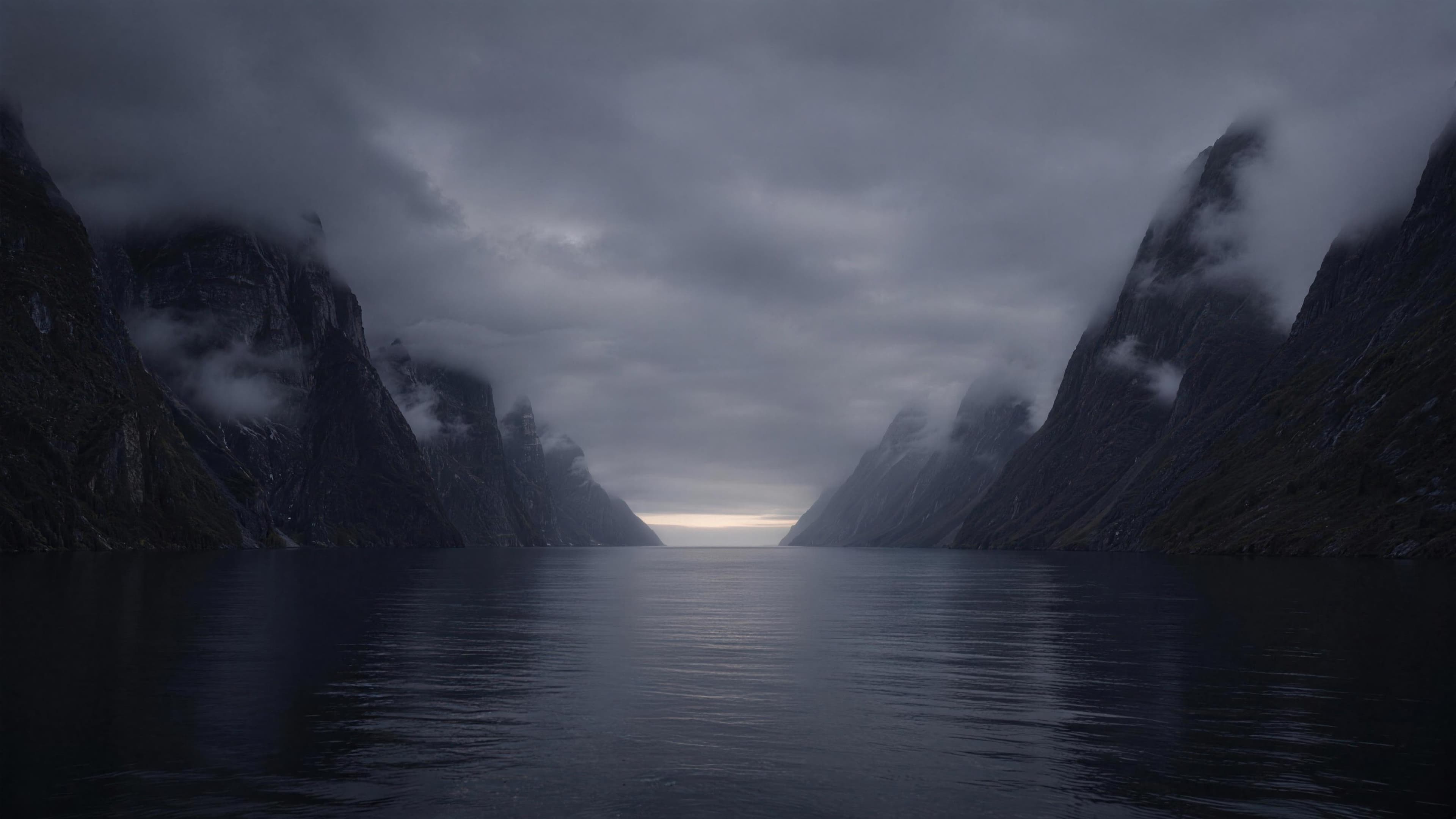 Stille fjord i skumring med bratte fjellsider og lavt skydekke.